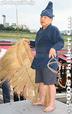 The fishing master's handmade skirt (koshimino) is made of straw. It functions as a raincoat and provides warmth. He makes and wears out four or five skirts each year.  Underneath is just shorts. 腰蓑（こしみの）
Keywords: gifu nagaragawa river ukai cormorant fishing fisherman birds boats