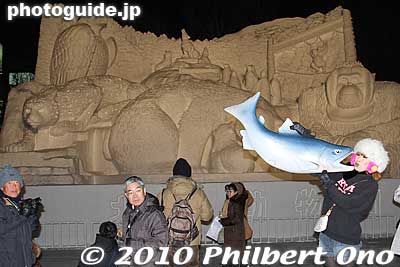 A cutie poses with a fake salmon in front of the Northland sculpture.
Keywords: hokkaido sapporo snow festival ice sculptures 