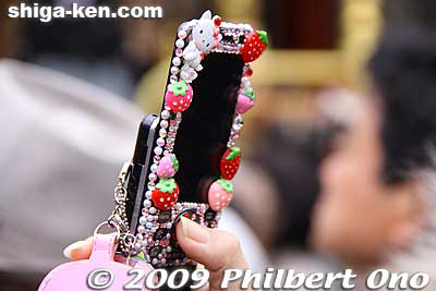 A young woman personalizes her cell phone to the max, making it a work of art (?).
Keywords: keitai cell phone