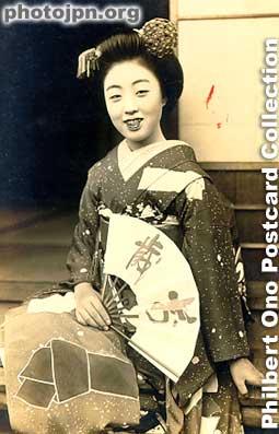 Smiling Maiko Sitting. Real-photo postcard to cheer up soldiers. This card was sent as military mail from Kyoto on New Year's Day 1939. The kanji characters on the fan says "Banzai," the traditional Japanese cheer for victory and happy occas
Real-photo postcard to cheer up soldiers. This card was sent as military mail from Kyoto on New Year's Day 1939. The kanji characters on the fan says "Banzai," the traditional Japanese cheer for victory and happy occasions. It also means "long life," something that soldiers would like.
Keywords: japanese vintage postcards nihon bijin women beauty geisha maiko woman kimono fan