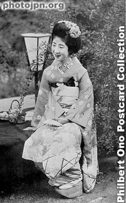 Smiling Maiko sitting in garden
Notice her left sleeve reaching the ground. A sign of a maiko's kimono, not a geisha's. Also, the high clogs that she wears are called pokkuri. Maiko wear them, but geisha do not.
Keywords: japanese vintage postcards nihon bijin women beauty geisha maiko woman kimono
