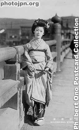 Maiko on Gojobashi Bridge. Postcard-size real photo taken in Kyoto. She has been poorly posed. Her posture is bad, her kimono is ruffled, the sleeves look bad, and her feet are pointing in the wrong direction. Maiko usually know how to pose themselves.
Postcard-size real photo taken in Kyoto. She has been poorly posed. Her posture is bad, her kimono is ruffled, the sleeves look bad, and her feet are pointing in the wrong direction. Maiko usually know how to pose themselves for a photograph. But not this one. Perhaps she's an amateur.
Keywords: japanese vintage postcards nihon bijin women beauty geisha maiko woman kimono kyoto