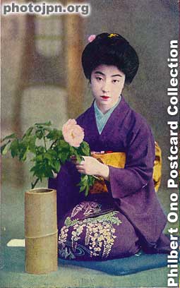 Flower arrangement. She's about to put the flower into the vase made of bamboo. On her lap, there's a pair of scissors used for flower arrangement. Her purple kimono has a design showing wisteria flowers. The season must have been spring.
The card was printed in color so it's not that old.
Keywords: japanese vintage postcards nihon bijin women woman beauty kimono flowers