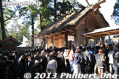 The people who went up the right edge of the steps didn't go through the torii and could only pray at a temporary, off-center position under the slim roof seen here on the right of the thatched-roof gate. 
Keywords: mie ise jingu shrine shinto hatsumode new year&#039;s day shogatsu worshippers