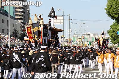 This is another part of the parade route. They are approaching an intersection called Can-Can-ba. 
Keywords: osaka kishiwada danjiri matsuri festival floats