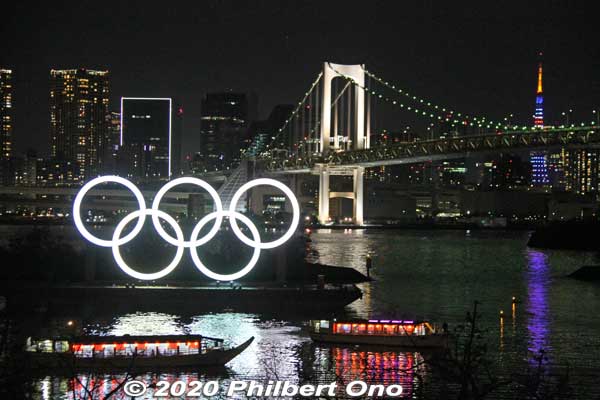 Olympic rings lit up in white in Odaiba with Rainbow Bridge and Tokyo Tower