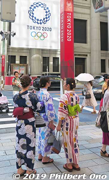Nihonbashi, Tokyo in Aug. 2019, yukata-clad women admire the Tokyo 2020 dressing