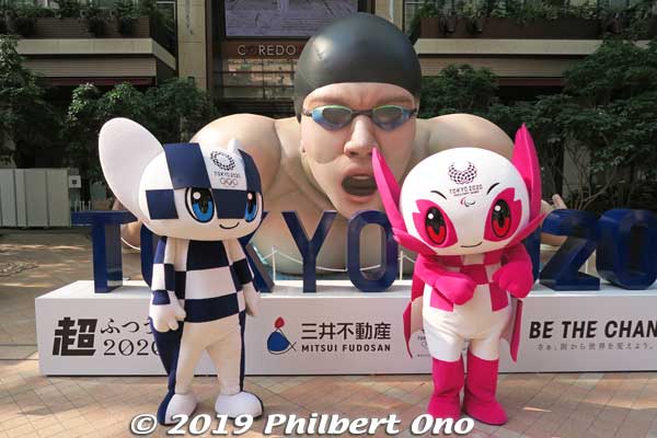 Super Unusual 2020 Exhibition: Miraitowa and Someity in front of a giant inflatable swimmer in Nihonbashi's Coredo M