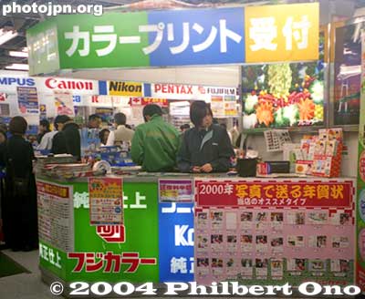 Photo Lab Counter
受付 - The last two characters on the large sign above is "uketsuke" meaning reception desk. This is a film processing counter inside a large camera store. The katakana characters before uketsuke say "Color Print." It's where to go to get your film processed.
