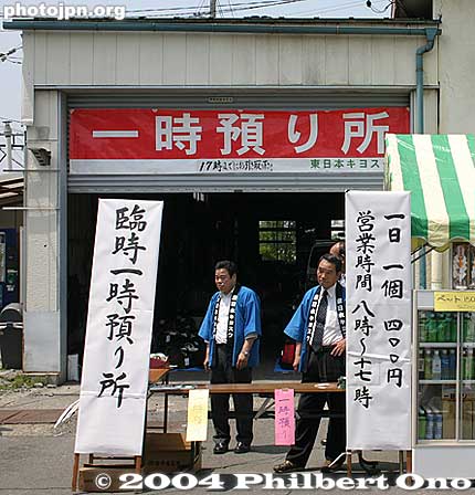Store Your Bags
一時預り所 - "Ichiji azukari-sho" means makeshift baggage storage place. This facility has been provided to accommodate the bags of the flood of visitors coming to see a big festival near this train station. The available coin-operated lockers are not enough. The "ichiji" can also mean one o'clock, but in this context, it means temporary. 

The sign on the right says, "Ichinichi ikko 400 yen" and "Eigyō jikan 8:00 - 17:00." It costs 400 yen to store one bag, and the storage hours are as stated. The place requires you to come back for your stored bag by 5 pm. One advantage of the coin-operated lockers is that you don't need to come back for your bag by 5 pm.

Place: Shimo-Suwa Station, Nagano for the Onbashira Festival.
