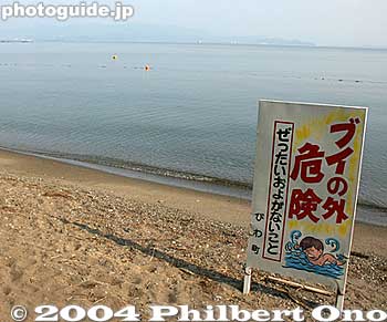 Do not Go Beyond the Buoys
ブイの外　危険 - It reads "Bui no soto kiken" which means "Dangerous to go beyond the buoy." The buoys in this case are the brightly-colored floating balls that mark the outer boundary of the safe swimming area. The water is usually too deep or the waves are too dangerous beyond this boundary. Almost all swimming beaches in Japan have some kind of outer boundary.

Place: Northern Lake Biwa, Shiga Pref.
Keywords: warning sign photographer