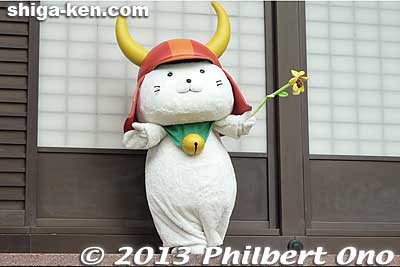 Hikone's official mascot Hiko-nyan appears three times daily for a 30-min. show: 10:30 am and 1:30 pm in front of the main castle tower (tenshu) and at 3:00 pm outside Hikone Castle Museum.
According to legend, one day, Ii Naotaka, the third lord of Hikone Castle, was doing falconry in Tokyo and was near a temple when he saw this cat raising its paw. He was led inside the temple where he was able to rest inside. A major thunderstorm ensued, and the cat saved him from getting wet.
Keywords: shiga hikone castle hikonyan hiko-nyan mascot yuru-kyara cat shigamascot