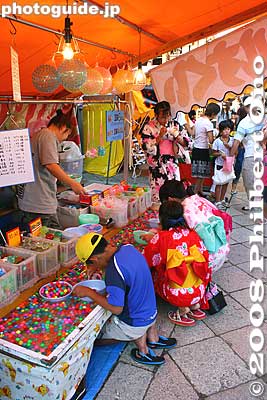 Kids catching small colorful balls in the water with a paper net.
Keywords: shiga nagahama kinomoto-cho jizo-in buddhist temple ennichi summer festival matsuri crowds