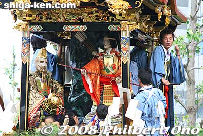 The float is associated with Empress Jingu of the 4th century. When she gestures to write some characters on a rock with her bow, and the characters magically appear.
Keywords: shiga otsu matsuri festival floats 