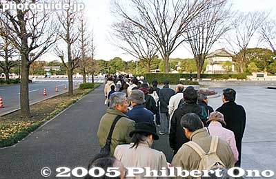 Dec. 23, 2004 at 8:30 am: Across the street from the Imperial Palace. Dec. 23 and Jan. 2 are the only two days when the general public is allowed to enter the palace to greet the Emperor and his family.
A visit to the Imperial Palace by the general public is called "ippan sanga" in Japanese （一般参賀）.

On the Emperor's birthday, the Imperial Palace can be entered only at certain locations. You have to find out where they are and stand in line there. Just go near the Imperial Palace and ask a policeman where you can stand in line. You otherwise cannot enter the grounds. The huge, graveled plaza where you can see Nijubashi Bridge is closed off by police. 

While standing in line here, we received free paper Japanese flags. 
Keywords: Tokyo Chiyoda-ku ward emperor akihito birthday Imperial Palace matsuri12