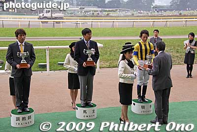 The winning horse's trainer, owner, and jockey receive a trophy during a ceremony.
Keywords: tokyo fuchu race course horse racing 