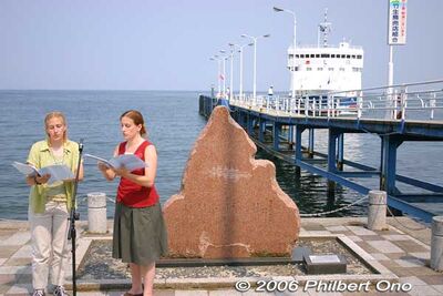 「琵琶湖周航の歌」英語版を初披露するジェイミーとメゲン・トンプソンの姉妹。滋賀県今津港の歌碑前にて。途中になんと「うみのこ」も歌を歓迎するように入港しました。「うみのこ」は、この歌の歌詞から名付けられて滋賀県立のフローティングスクールで琵琶湖での児童学習航海をやっています。2006年06月03日