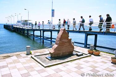 今津港で全歌詞碑（手前）と桟橋の先にランプ形の三番の歌碑が小さく見えます。今津港では竹生島行きの船があります。４月には海津大崎への桜クルージも出発します。